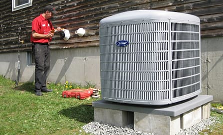 Air-Pro technician in a red shirt working beside a new Carrier outdoor air conditioning unit